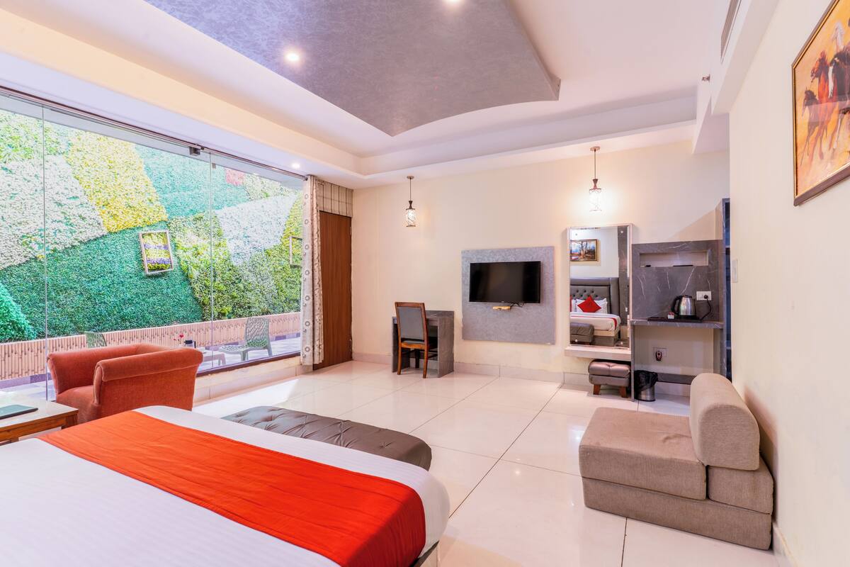 A hotel room with a bed, a sofa, a TV, a fireplace, and a balcony with a view.