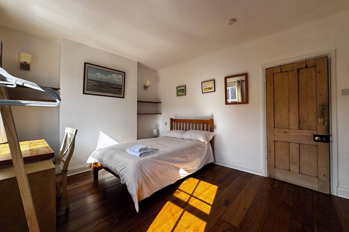 A bedroom with a wooden bed, a chair, a desk, and a wardrobe.
