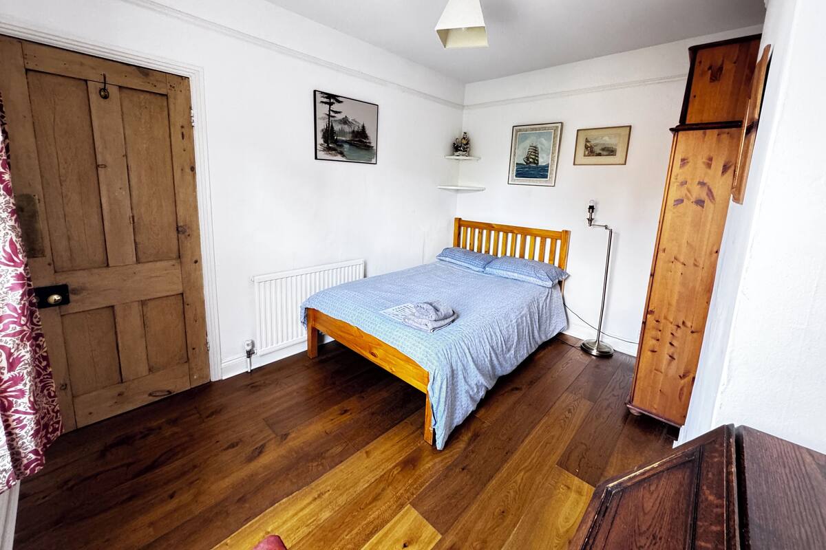 A bedroom with a wooden bed, white walls, and a radiator.