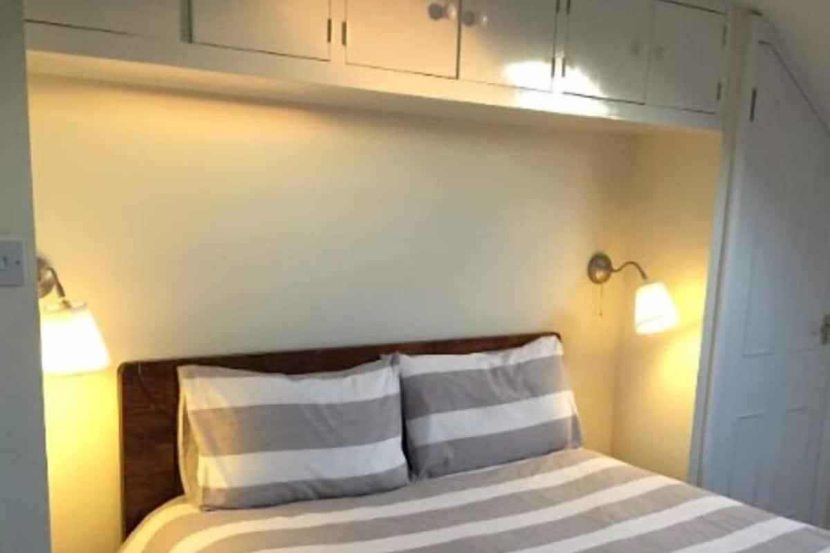 A bed with striped bedding, two bedside lamps, and a wooden headboard.