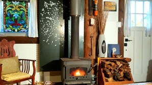 Una sala de estar acogedora con una estufa de leña, una ventana de vitral y una silla de madera rústica.