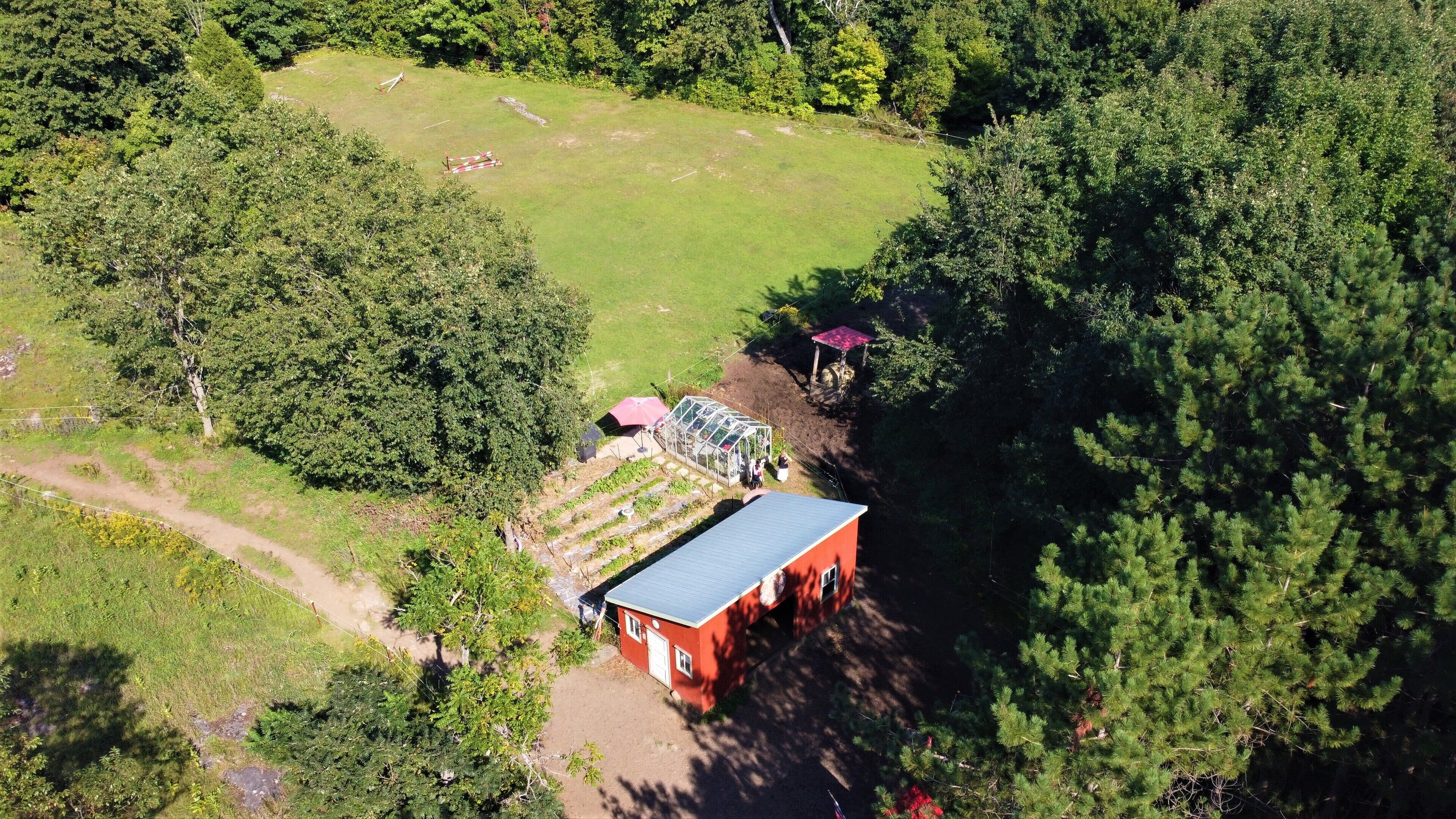 Luchtbeeld van een pand met een kas, een rood gebouw en een omheind tuingebied.