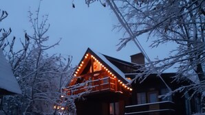 Una cabaña de madera con balcón, rodeada de árboles cubiertos de nieve.