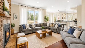 A living room with a fireplace, two grey sofas, a coffee table, and a view of the outdoors.