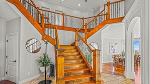 A grand wooden staircase with a curved design, leading to a dining area with a view.