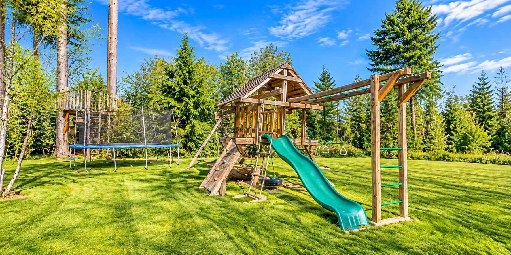 Ein Spielplatz mit Rutsche, Kletterwand und Schaukeln.
