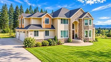 A two-story house with a stone facade, a driveway, and a well-maintained lawn.