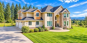 A two-story house with a stone facade, a driveway, and a well-maintained lawn.