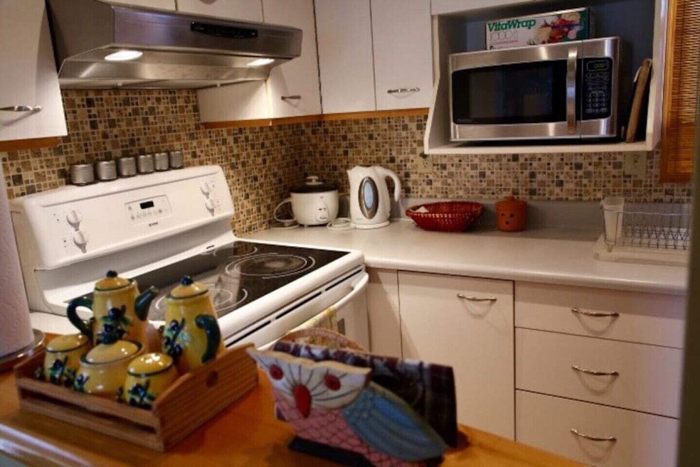 A kitchen with white cabinets, a stove, a microwave, and a tiled backsplash.