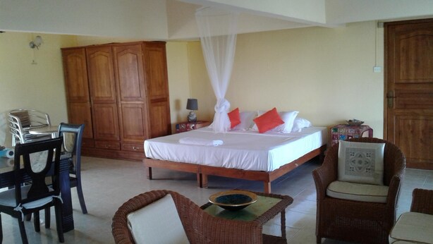 A hotel room with a bed, a desk, wicker chairs, and a wardrobe.