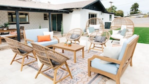 Eine Terrasse mit Korbmöbeln, einem Holztisch und einem blauen Sofa.