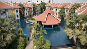 Una amplia piscina con un pabellón central, rodeada de edificios de varios pisos con tejados de tejas rojas.