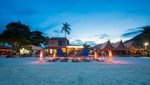 A beachfront hotel with a central building, multiple roofed structures, and a sandy beach area with lounge chairs. - Apartment By Sunrise Resort (Ko Pha-ngan)