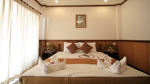 A neatly made bed with a brown headboard, white bedding, and decorative pillows. There is a framed artwork on the wall above the bed. - Apartment By Sunrise Resort (Ko Pha-ngan)