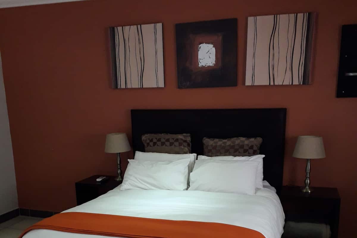 A hotel room with a large bed, two bedside tables, and a nightstand.