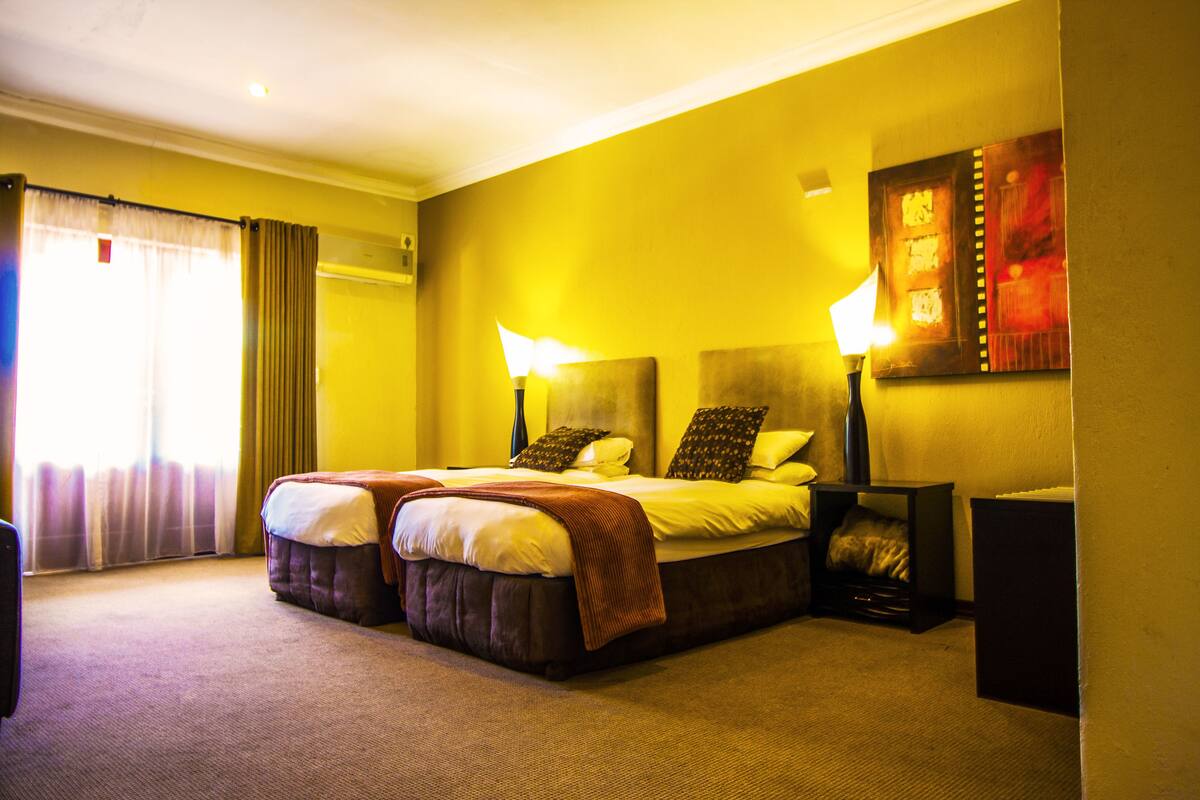 A hotel room with a large bed, two bedside lamps, a nightstand, and a painting on the wall.