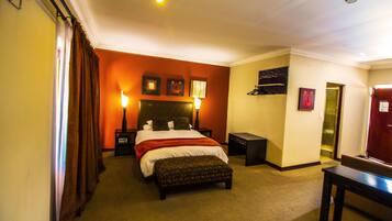 Relax in comfort with a large bed, a headboard with decorative design, and a bedside table with a lamp.