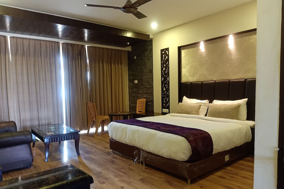 A hotel room with a large bed, a desk, a chair, and a ceiling fan.