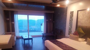 Habitación de hotel con cama, escritorio, silla y balcón con vistas a las montañas.