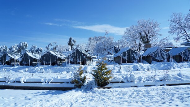 Una hilera de cabañas cubiertas de nieve bajo un cielo azul despejado.