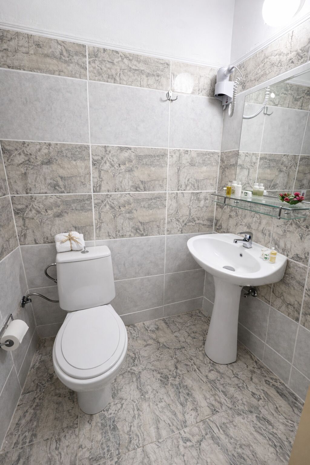 Un baño con inodoro, lavabo y baldosas de mármol.