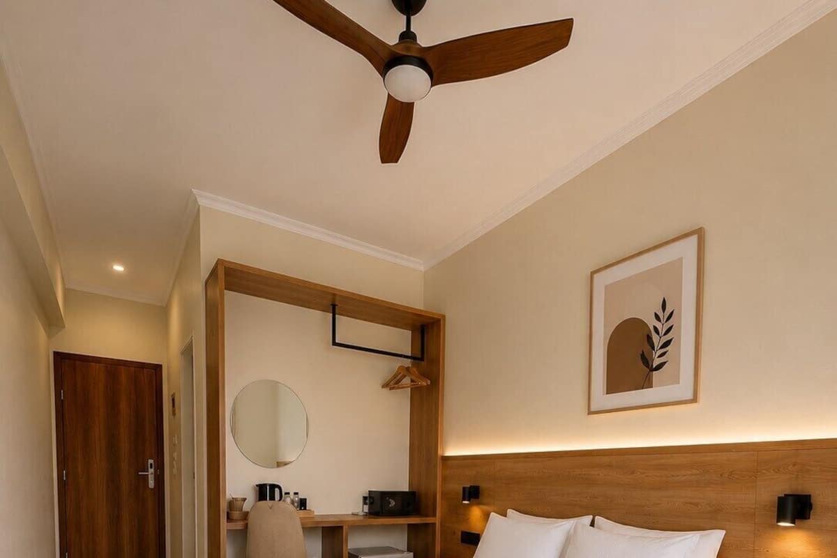 Quarto com cama, mesas de cabeceira, escrivaninha, cadeira, ventoinha no teto, espelho e quadro na parede.