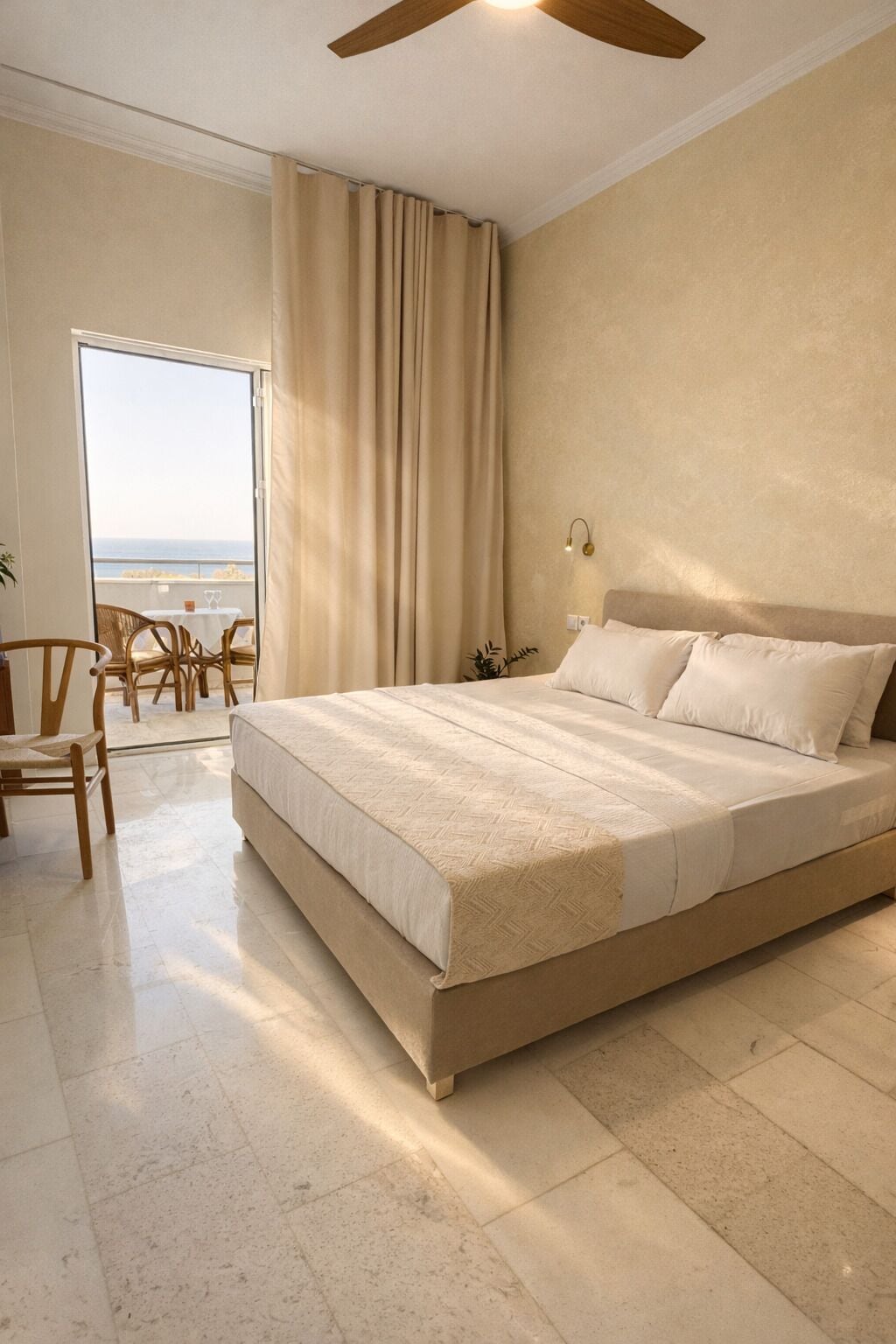 Un dormitorio amplio con una cama grande, un ventilador de techo y vistas al océano a través de un ventanal corredero.