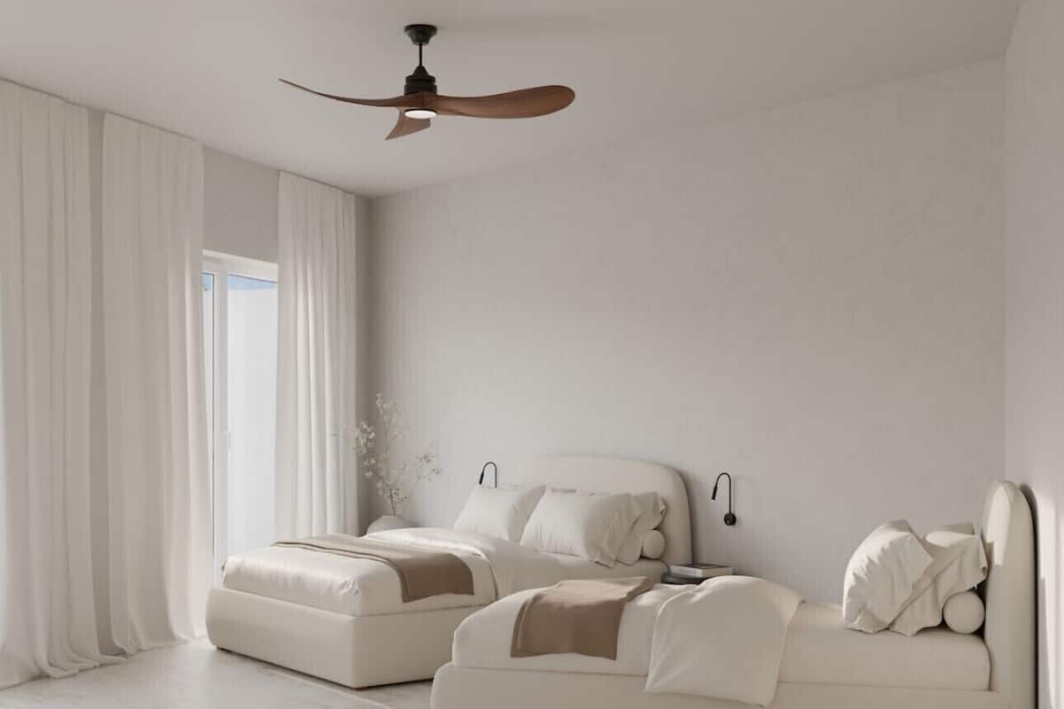 Quarto moderno com uma cama grande, um sofá menor, um ventilador de teto e uma janela com cortinas.