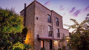 A stone building with a tiled roof, multiple windows, and a garden area with potted plants and a pathway. - Villa Denise (Vico Equense)