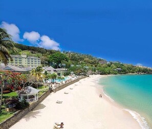 Une plage avec un complexe hôtelier, une eau turquoise et limpide, et une rive sablonneuse.