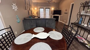Un coin repas avec une table ronde, quatre chaises et un ventilateur de plafond.