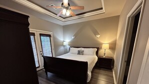 Une chambre à coucher avec un lit en bois, un ventilateur de plafond, une table de chevet avec une lampe et une porte avec une fenêtre.
