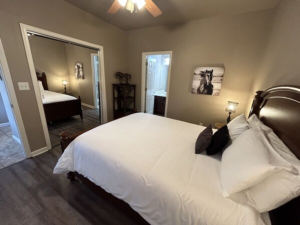 A bedroom with a large bed, a nightstand, a wall-mounted lamp, and a door leading to another room. - Charming, Conveniently Located Hot Springs Condo (Hot Springs)