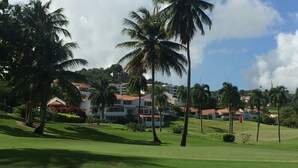 A golf course with palm trees and a building complex in the background.
