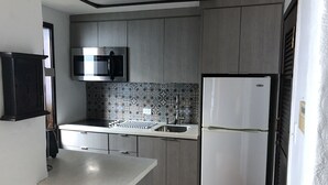 A compact kitchen with a microwave, refrigerator, and a sink.