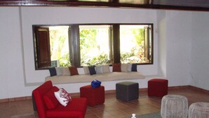 A living room with a red sofa, a grey ottoman, and a coffee table with chess pieces.