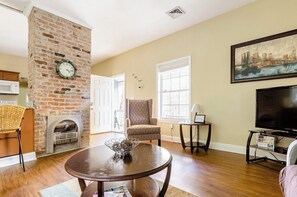 Cozy seating area with a fireplace, flat-screen TV, and large window.