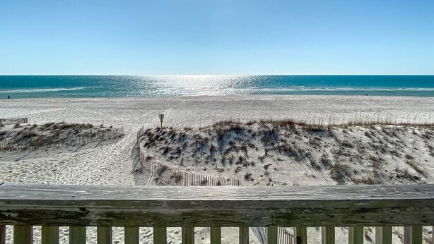 A beach with a wooden fence and dunes in the foreground. - Sunrise Village 201 - Private balcony right on the (Gulf Shores)
