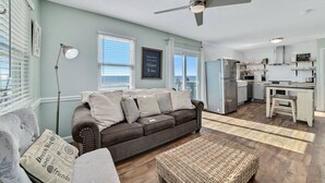 A cozy living room with a sofa, a coffee table, and a ceiling fan. - Sunrise Village 201 - Private balcony right on the (Gulf Shores)