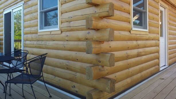 Une cabane en rondins avec une terrasse, une table et des chaises.