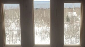 Trois fenêtres donnant sur un paysage enneigé et sur un navire au loin.
