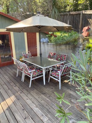 A wooden deck with a table and chairs, an umbrella, and a door. - Enjoy a Slice Of Country--Two miles to Downtown Healdsburg  (Healdsburg)