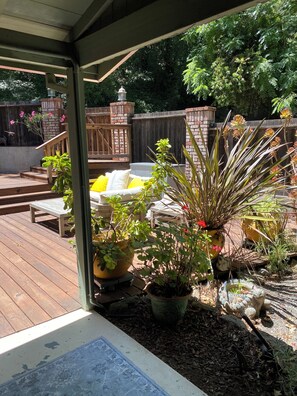A wooden deck with outdoor furniture, potted plants, and a brick wall in the background. - Enjoy a Slice Of Country--Two miles to Downtown Healdsburg  (Healdsburg)