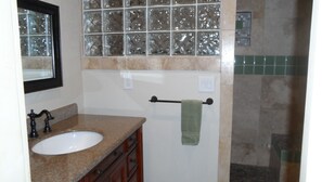 A bathroom with a granite countertop sink, a mirror, a towel rack with a green towel, and a glass shower enclosure. - Enjoy a Slice Of Country--Two miles to Downtown Healdsburg  (Healdsburg)