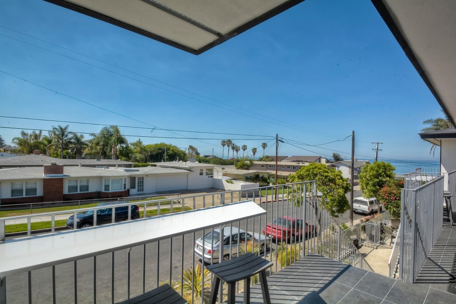 Un balcone con vista su una zona residenziale, tra case e auto parcheggiate.