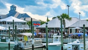 A marina with boats docked, a restaurant with outdoor seating, and a building with a pointed roof. - Beachfront/Pool Murrells/GardenCity/Surfside 
Wkly/MilitaryFirePoliceNurse Discs (Murrells Inlet)