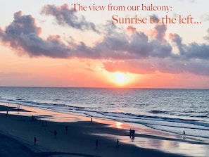 Ein Sonnenuntergangsblick von einem Balkon mit Blick auf einen Strand, an dem Menschen entlang der Küste spazieren.