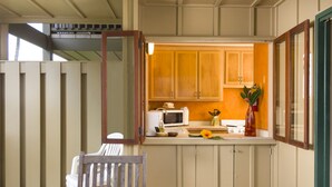Una cocina con armarios de madera, un microondas y una mesa con sillas.
