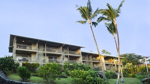 Un hotel de varios pisos con balcones, rodeado de follaje tropical y palmeras.