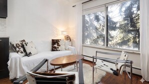 Ein modernes Zimmer mit einem weißen Sofa, einem Holztisch und einem Metallstuhl.